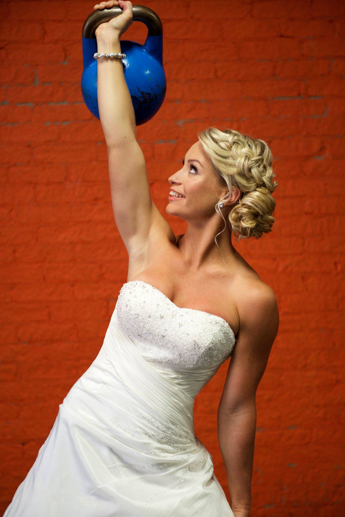 Picture of Shannon in a wedding dress, lifting a heavy kettlebell over her head